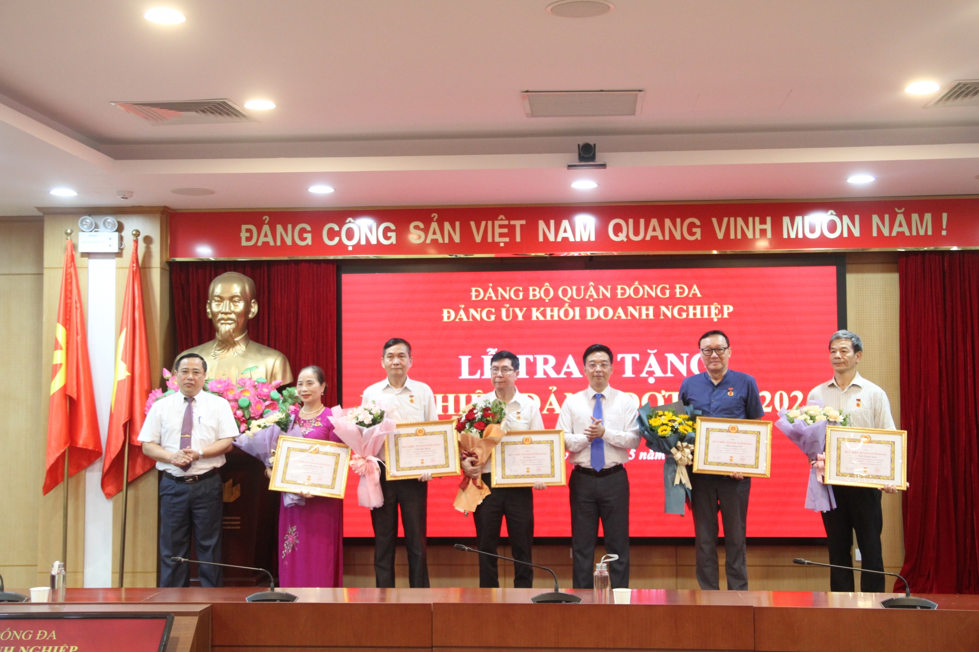 Đồng chí Vũ Mạnh Chiến và đồng chí Nguyễn Văn Quang trao và tặng hoa chúc mừng các đồng chí Đảng viên được nhận Huy hiệu 30 năm tuổi Đảng