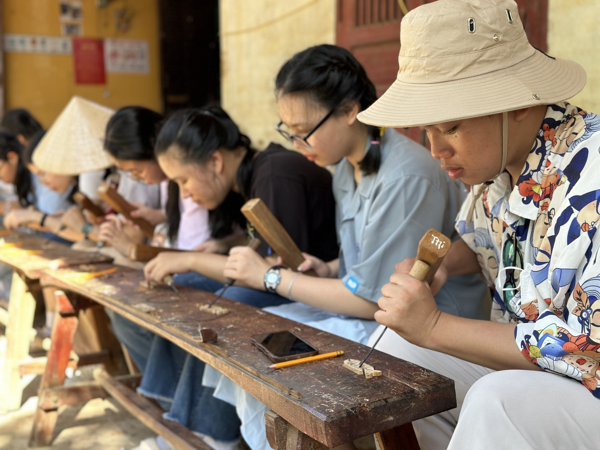 Các bạn trẻ say mê trải nghiệm hoạt động chạm khắc mộc tại các làng nghề ở Hội An.