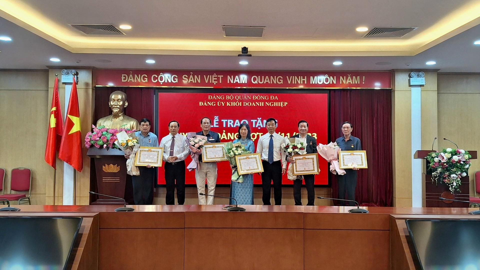 Đồng chí Vũ Mạnh Chiến và đồng chí Nguyễn Văn Quang trao và tặng hoa chúc mừng các đồng chí Đảng viên được nhận Huy hiệu Đảng đợt 7/11/2023